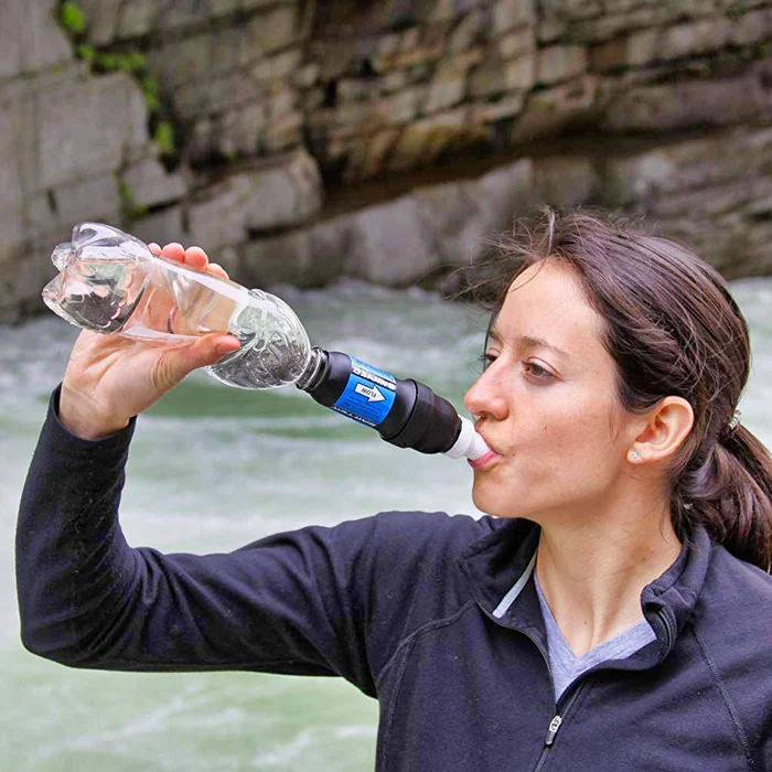 Filtro de agua portátil Sawyer Squeeze siendo usado con una botella de agua.